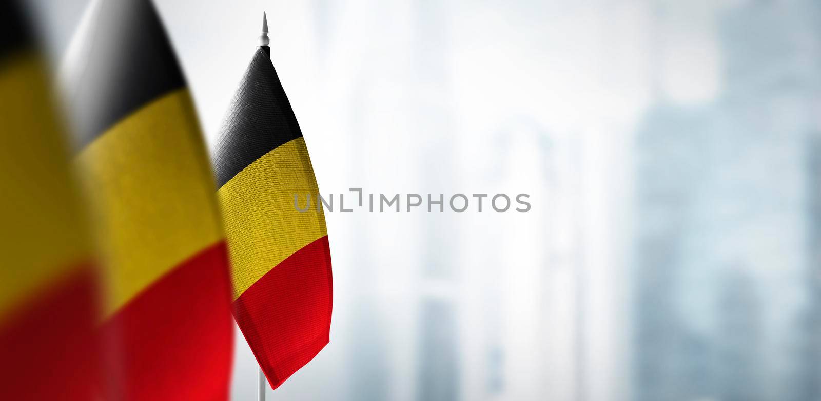 Small flags of Belgium on a blurry background of the city.