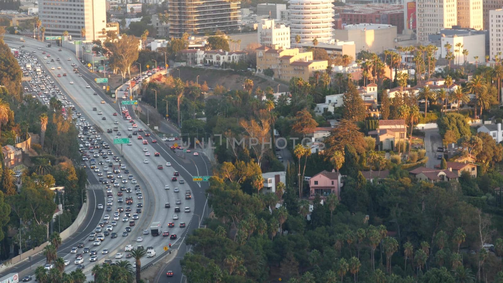 Busy rush hour intercity highway in metropolis, Los Angeles, California USA. Urban traffic jam on road in sunlight. Aerial view of cars on multiple lane driveway. Freeway with automobiles in LA city by DogoraSun