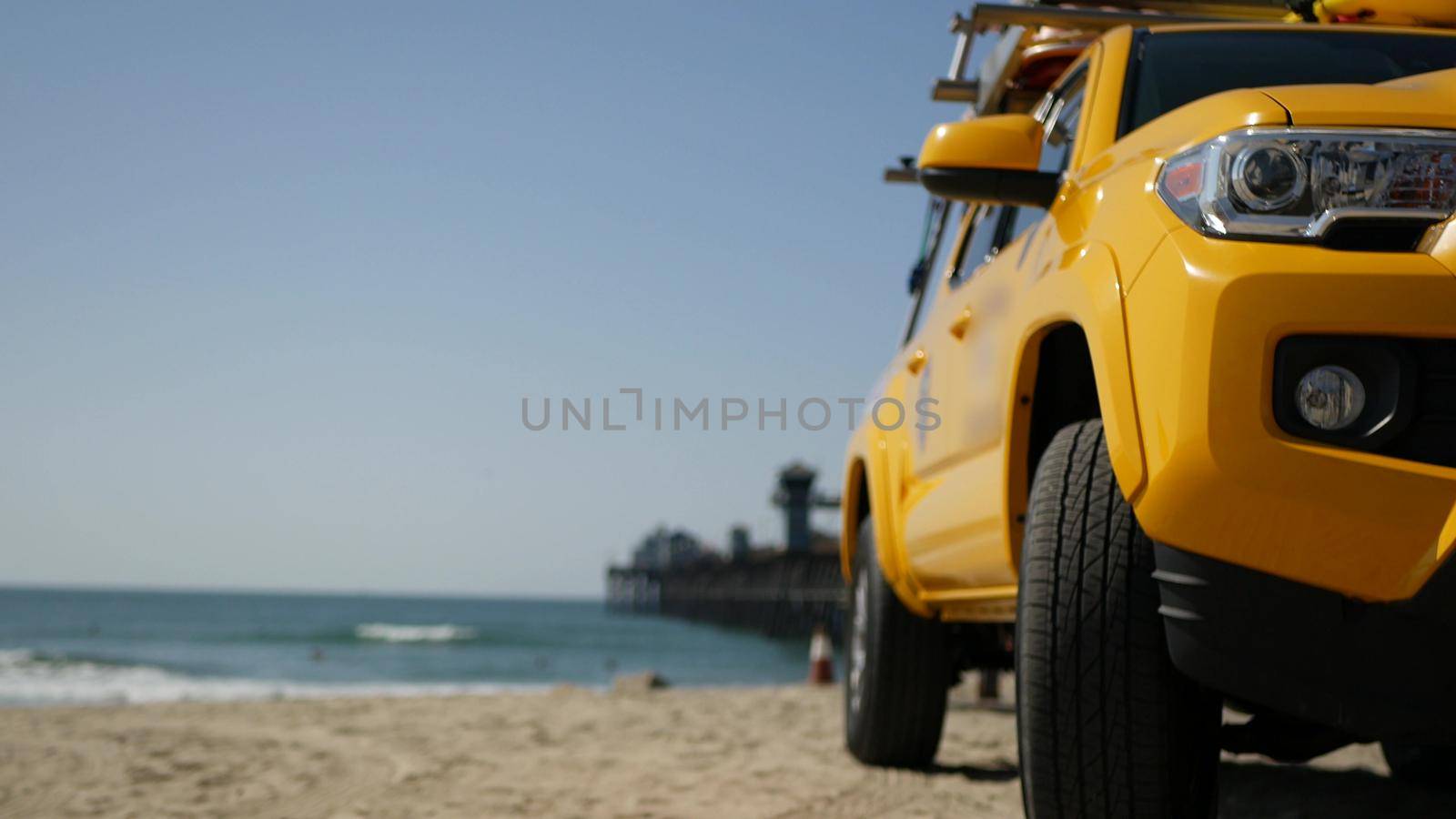 Yellow lifeguard car, Oceanside beach, California USA. Coastline rescue life guard pick up truck, lifesavers vehicle. Iconic auto and ocean coast. Los Angeles vibes, summertime aesthetic atmosphere.