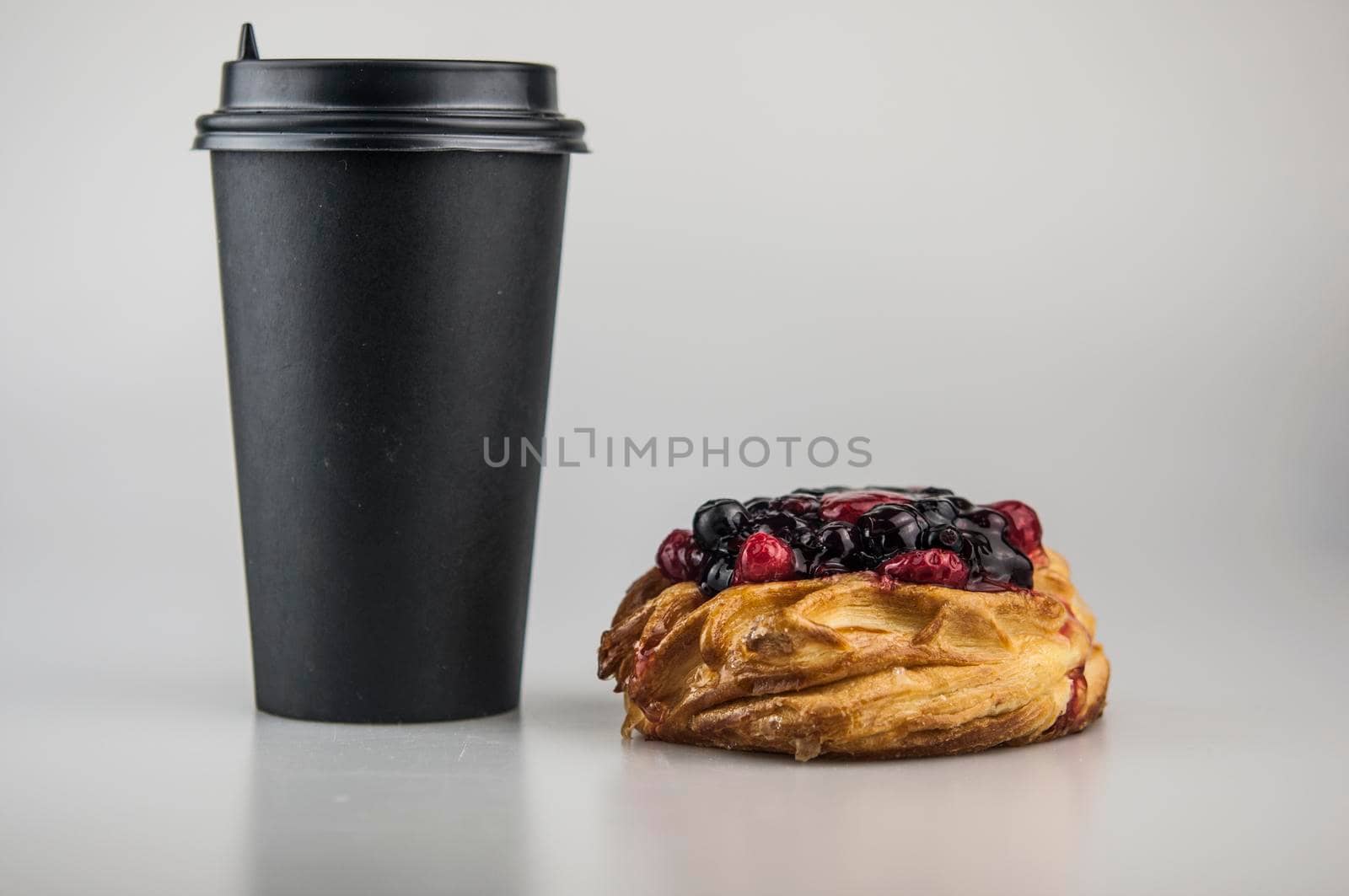 Delicious berries pastries with paper disposable coffee cup on a white background. Breakfast