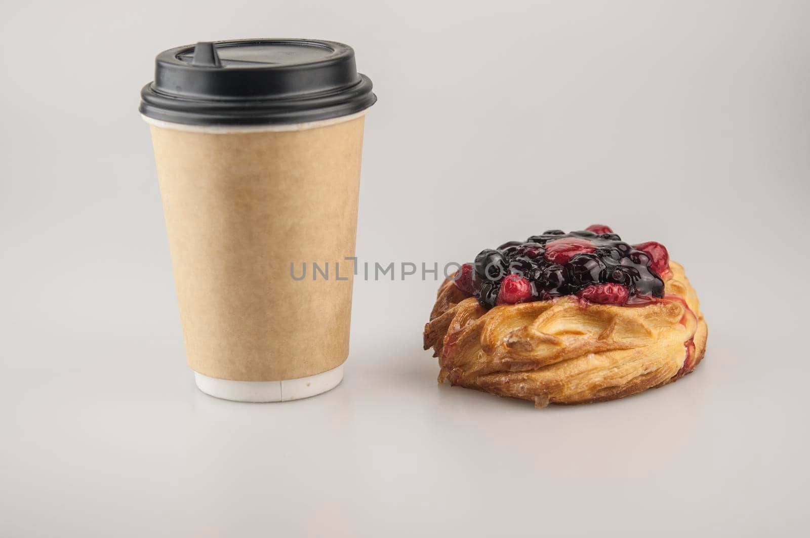 Delicious berries pastries with paper disposable coffee cup on a white background. Breakfast