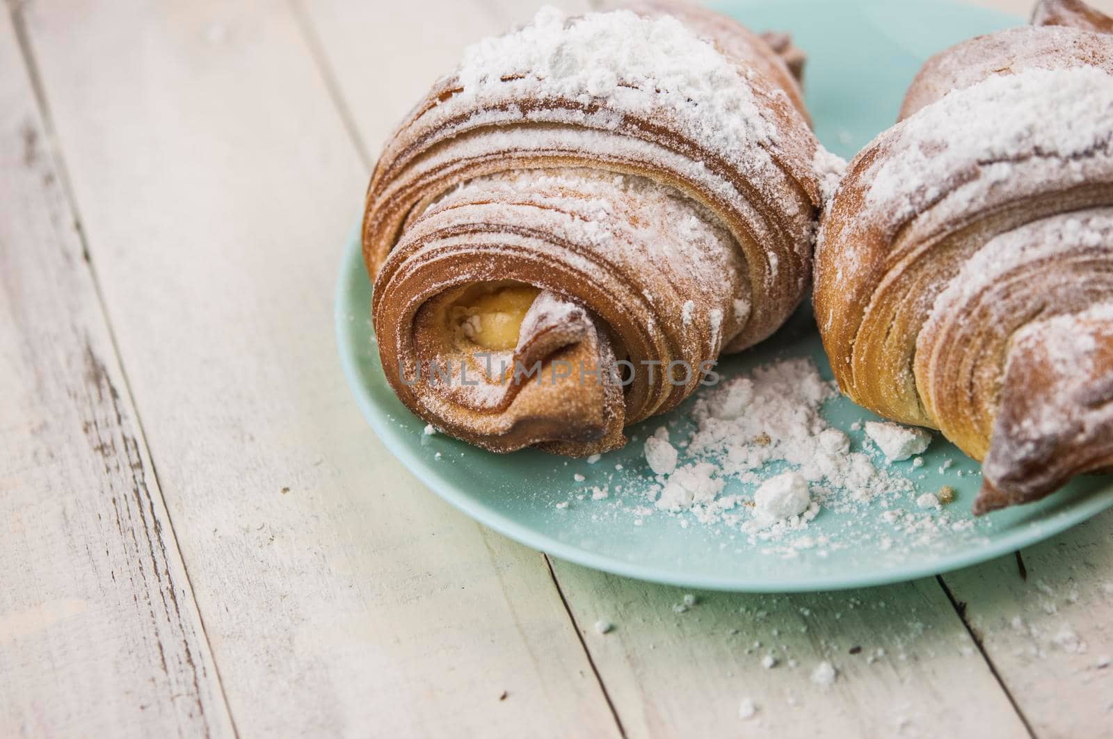 Two fresh croissants in plate on white wooden table. Breakfast