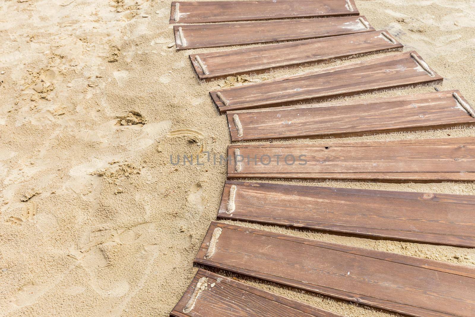 Wooden beach boardwalk, path with sand with copy space