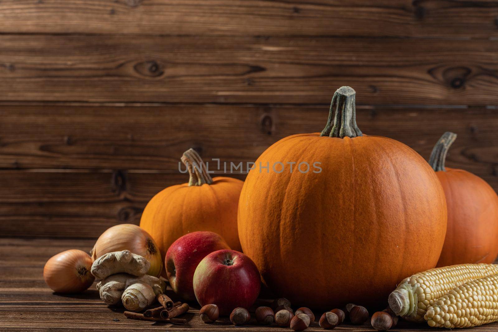 Autumn harvest still life with pumpkins, apples, hazelnut, corn on wooden background with copy space for text