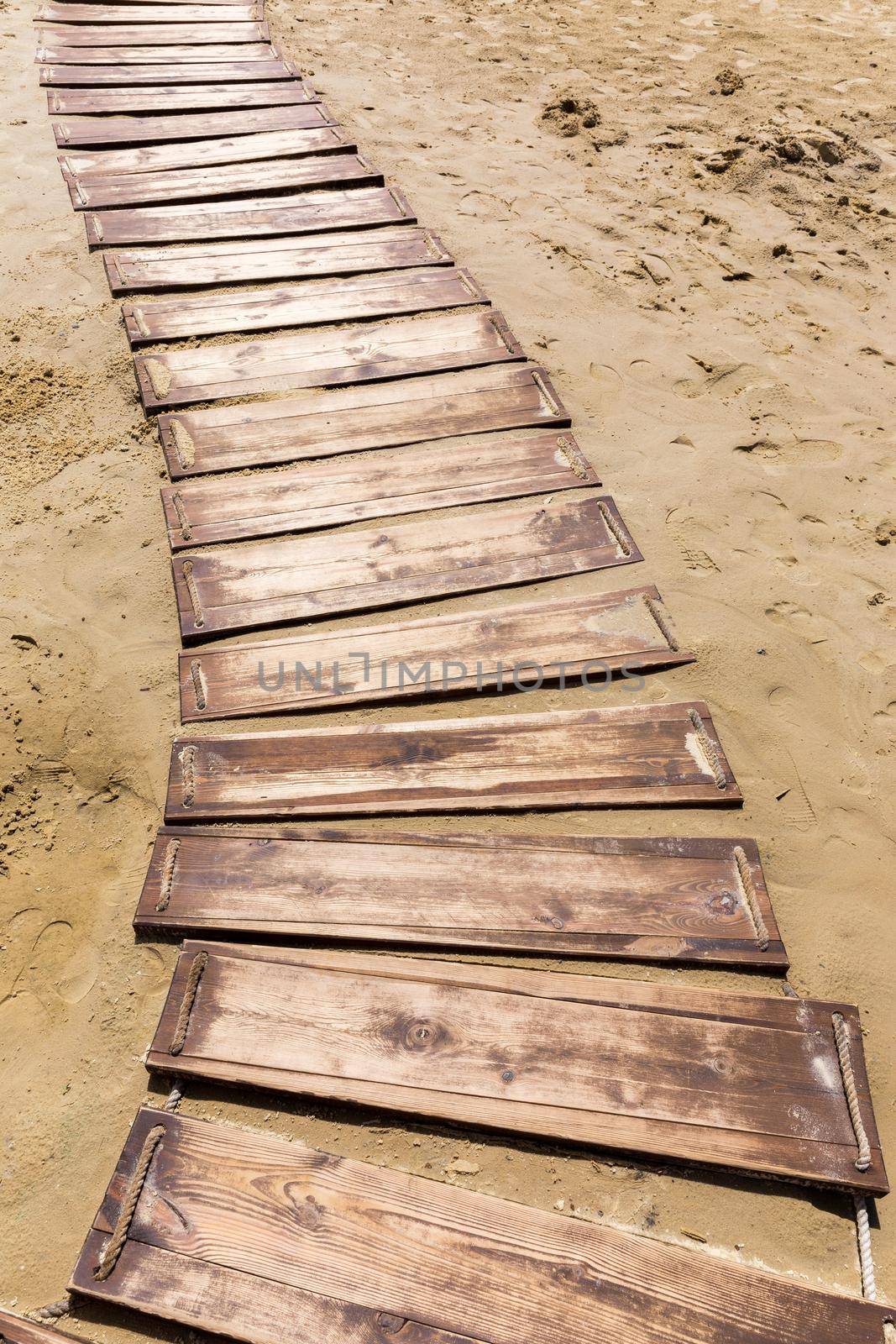 Wooden beach boardwalk, path with sand with copy space