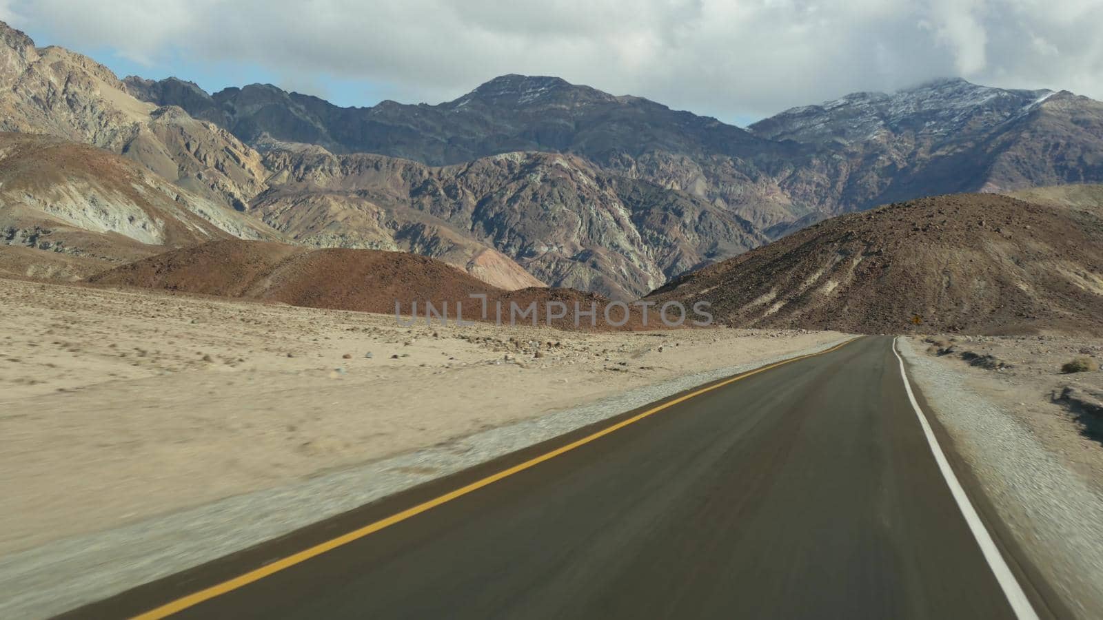 Road trip to Death Valley, Artists Palette drive, California USA. Hitchhiking auto traveling in America. Highway, colorful bare mountains and arid climate wilderness. View from car. Journey to Nevada by DogoraSun
