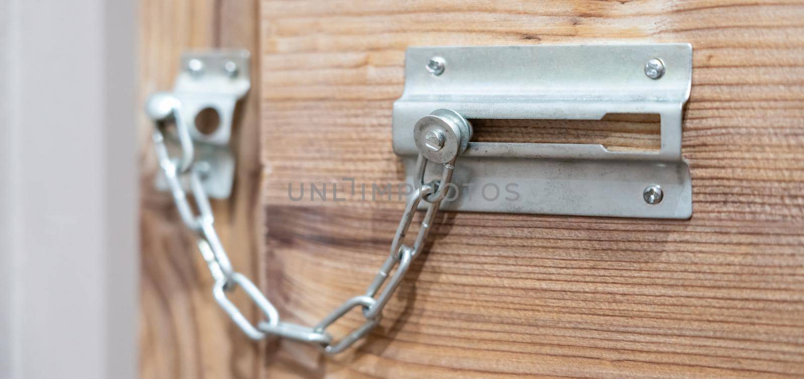 Close up of security door chain on a wooden door