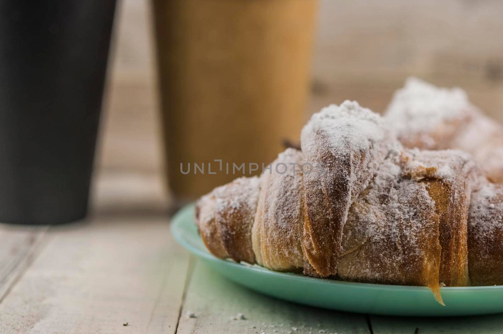 Two fresh croissants in plate on white wooden table. Breakfast