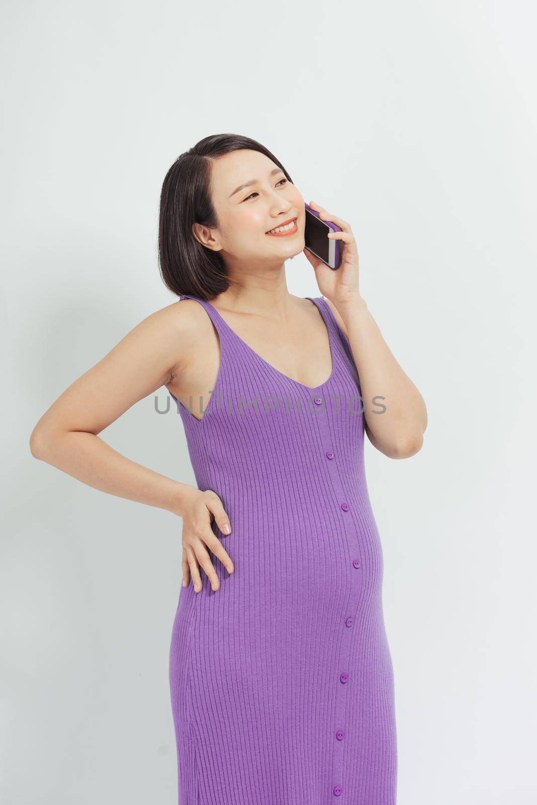 Portrait of latin pregnant woman talking on the phone against white background. Communication and pregnant concept.
