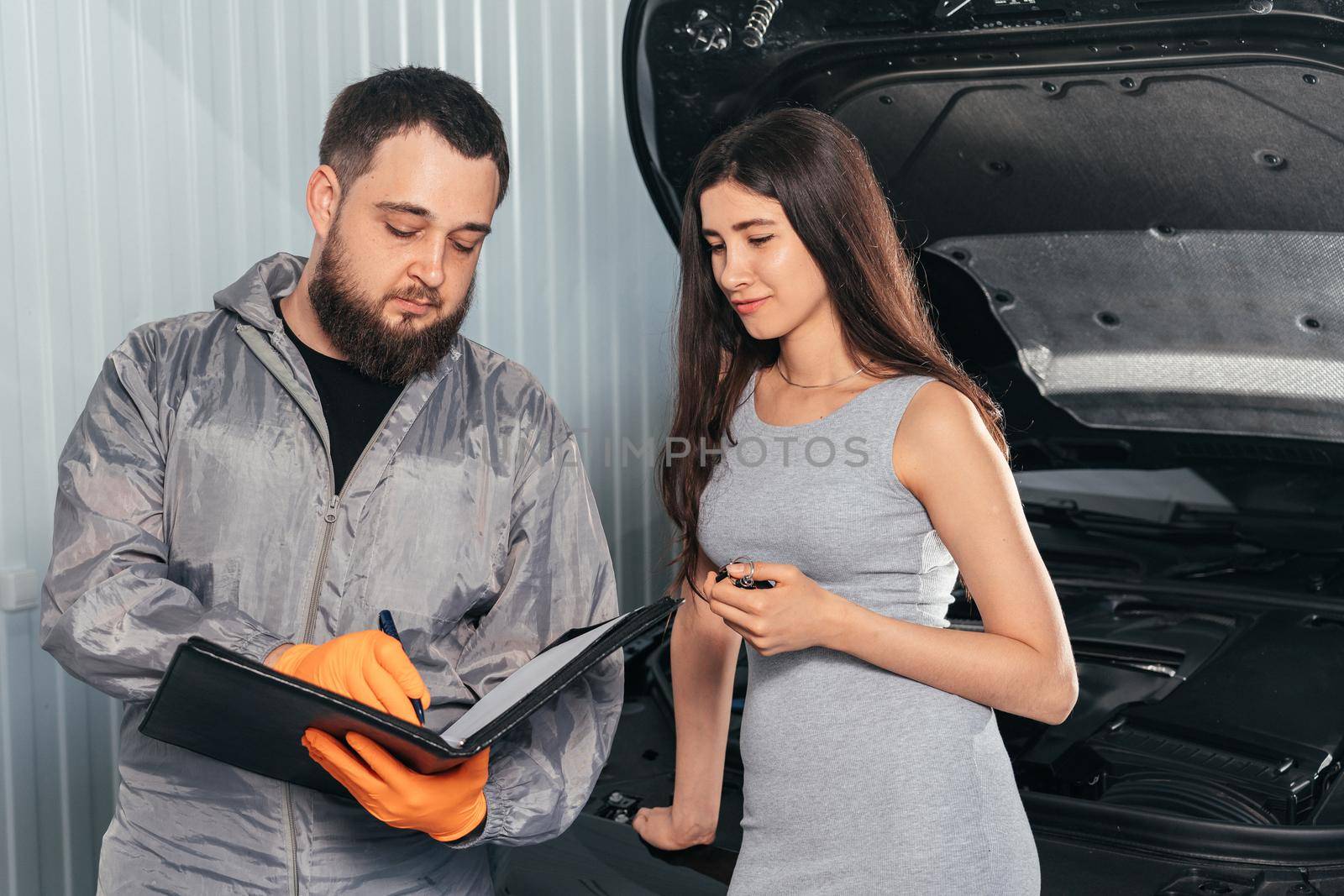 Auto Mechanic explains vehicle repair invoice to a female customer and signing papers
