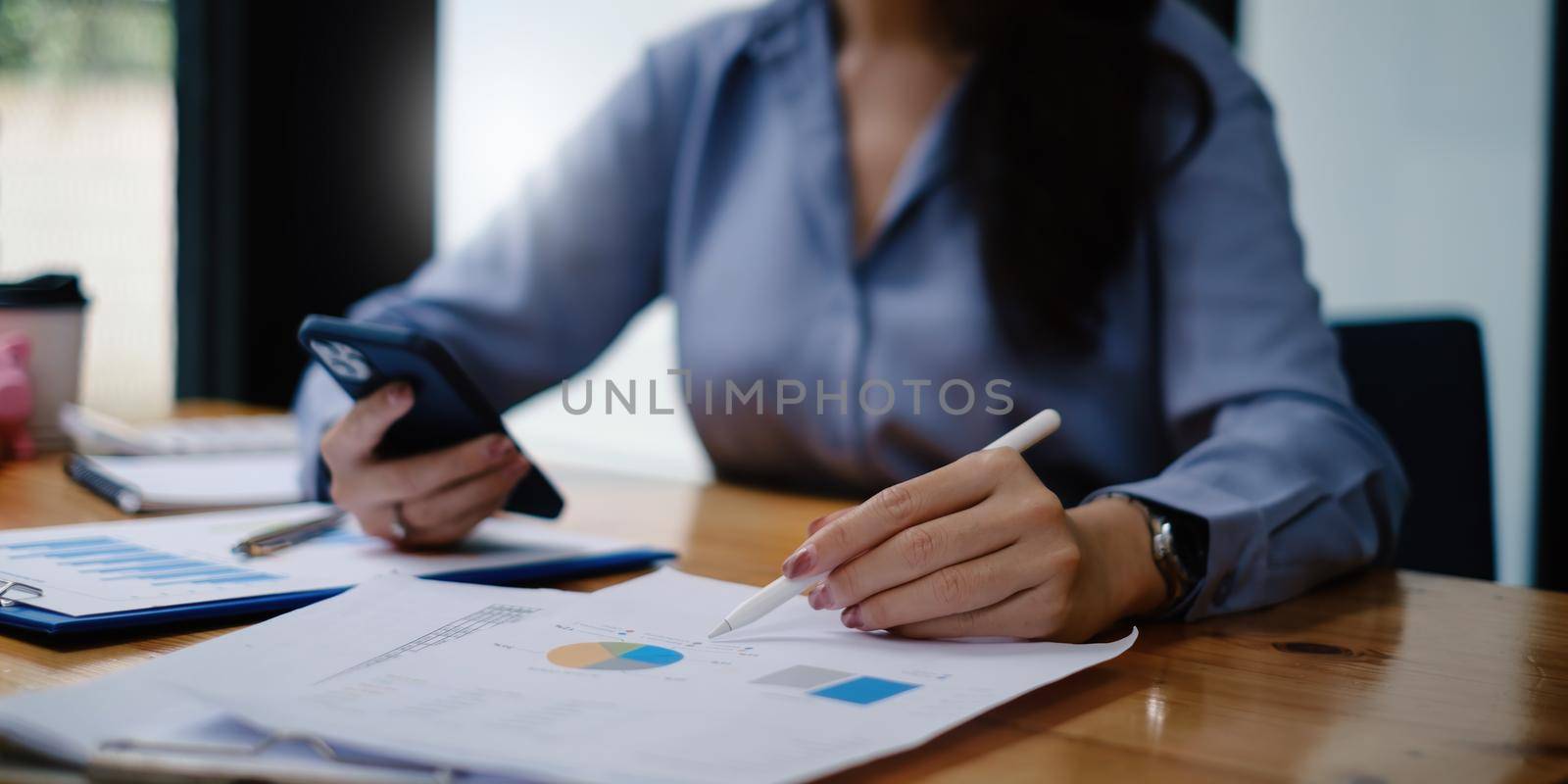 Business woman hand holding pen and cell phone with bank savings account application, account or saving money or insurance concept. by itchaznong