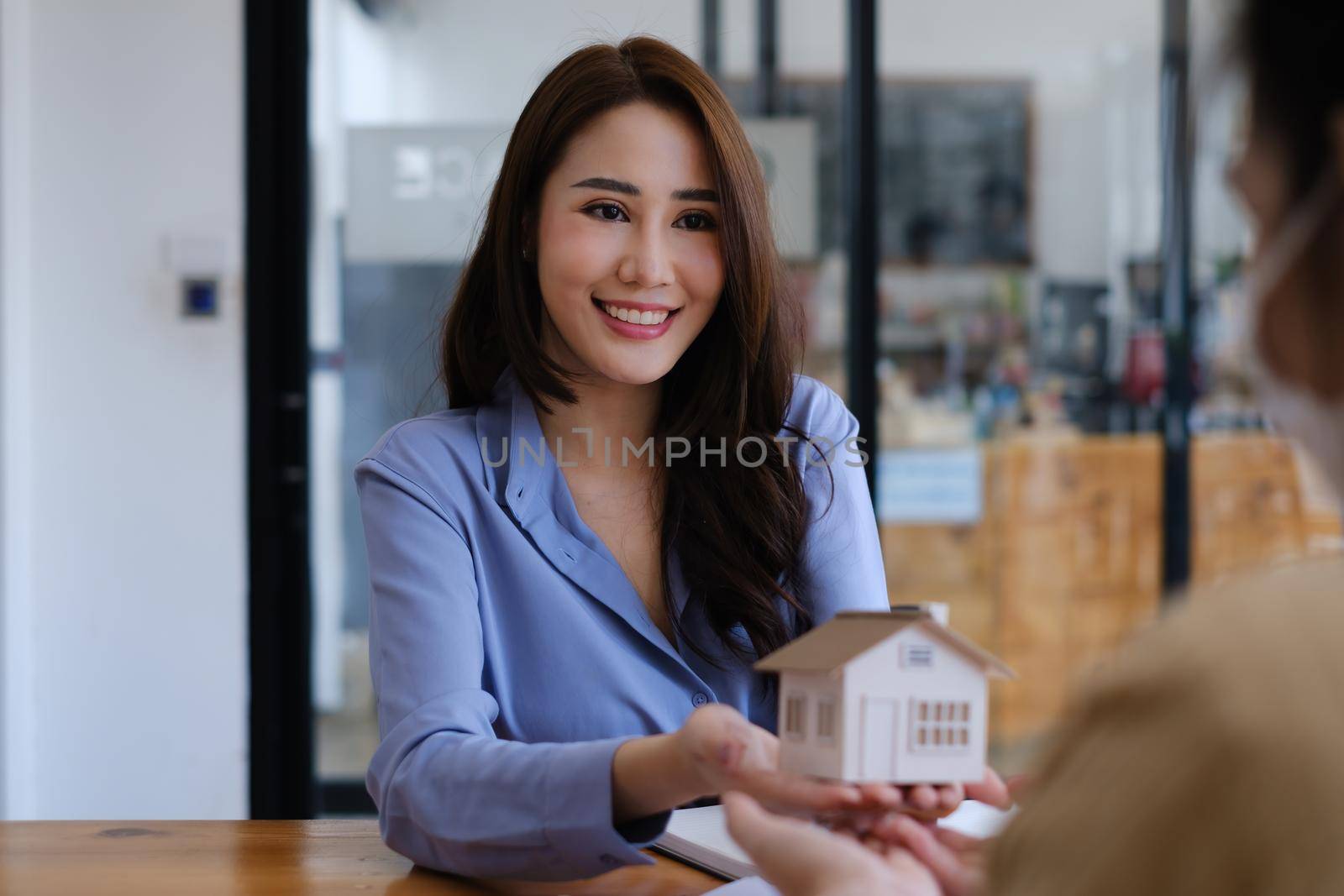 A real estate agent demonstrates the House model to clients interested in purchasing house insurance. The concept of home insurance and property