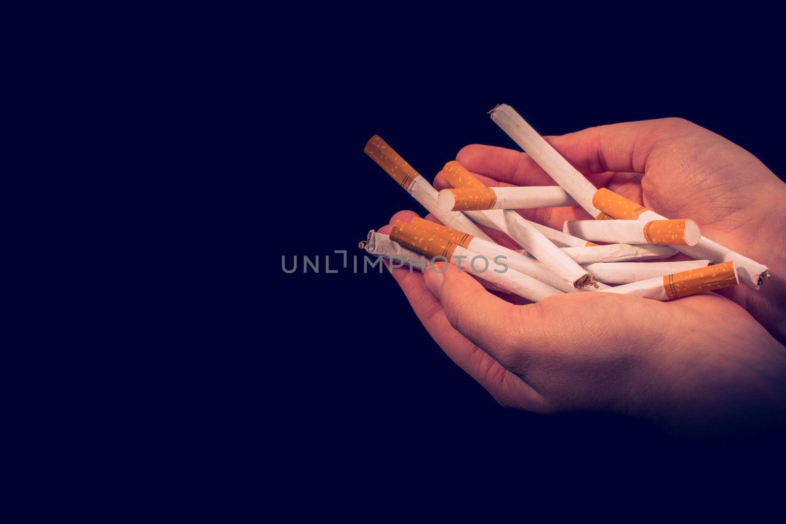 Hand is giving out cigarettes on a black background