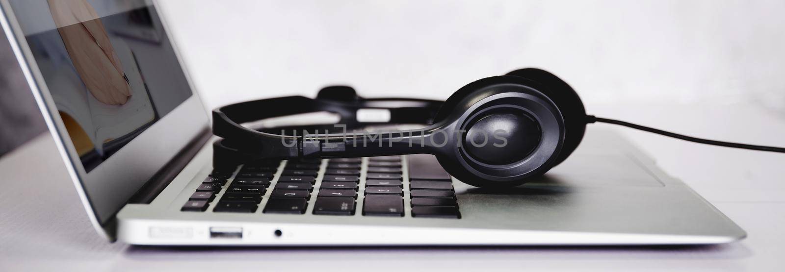 Laptop computer and headphone on desk, e-learning online, webinar for education and learning, seminar with notebook, video conference, headset for multimedia, course and classroom to internet. by nnudoo
