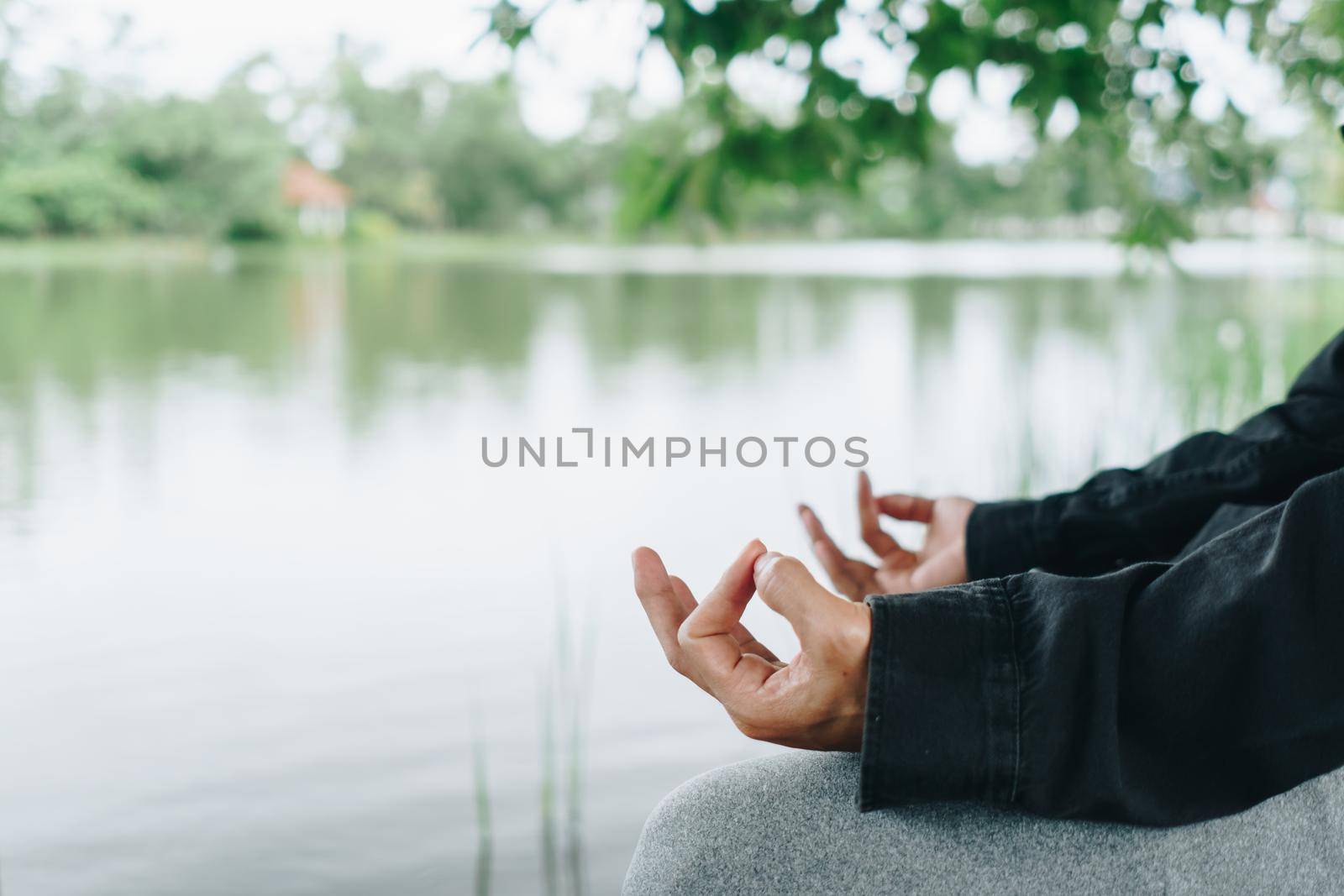 Woman practicing yoga lesson, breathing, meditating exercise, outdoor in grass field. Well being, wellness. by Suwant