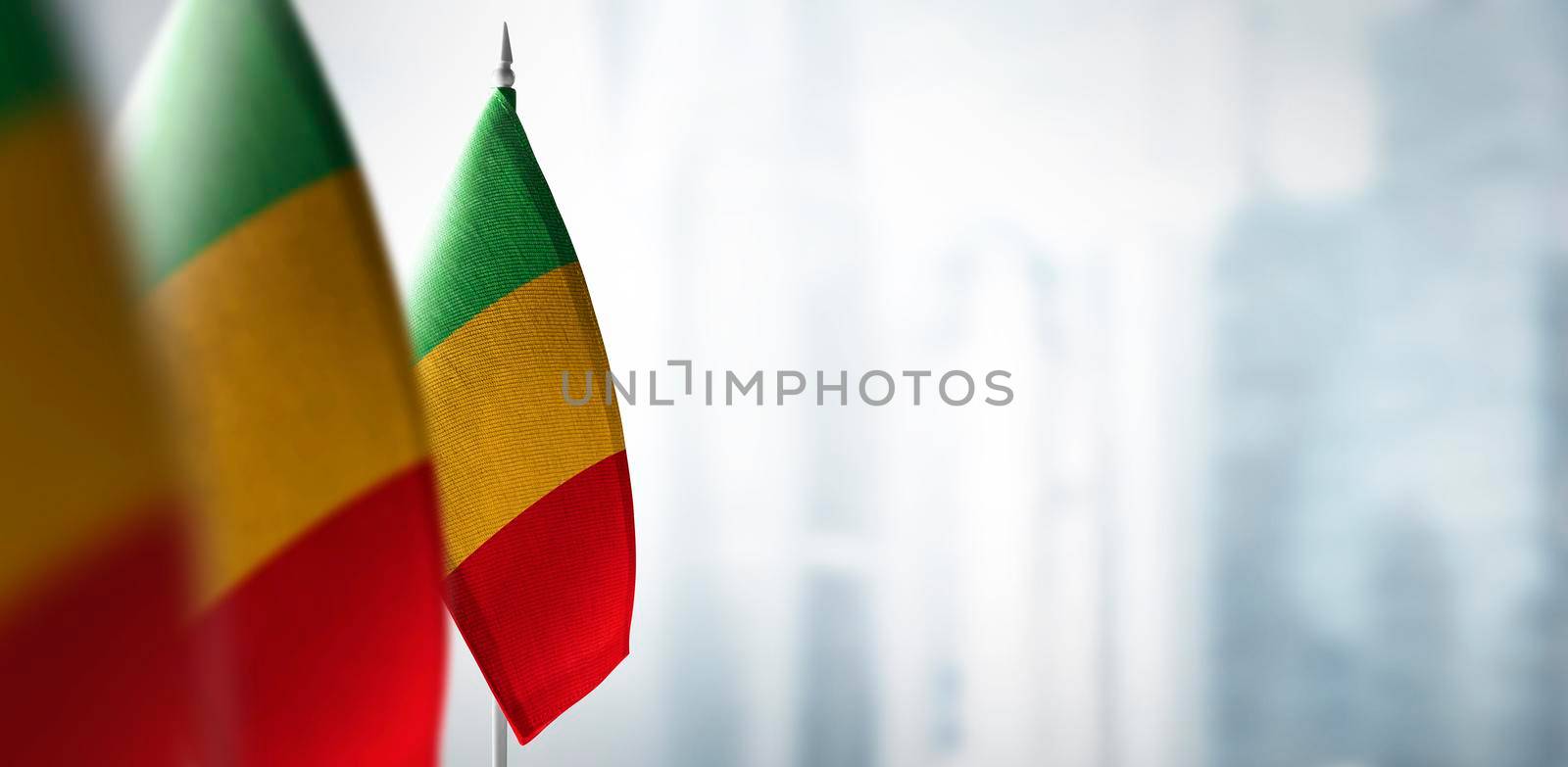 Small flags of Mali on a blurry background of the city by butenkow