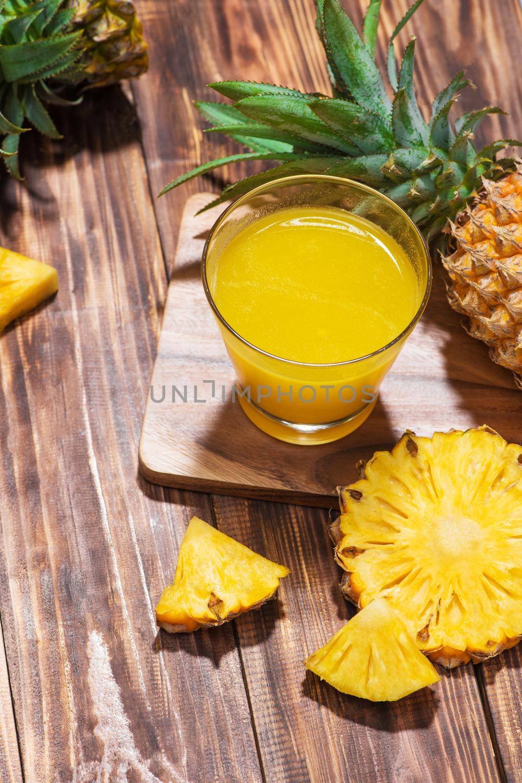 Fresh pineapple juice in the glass with pineapple fruit on wooden background.