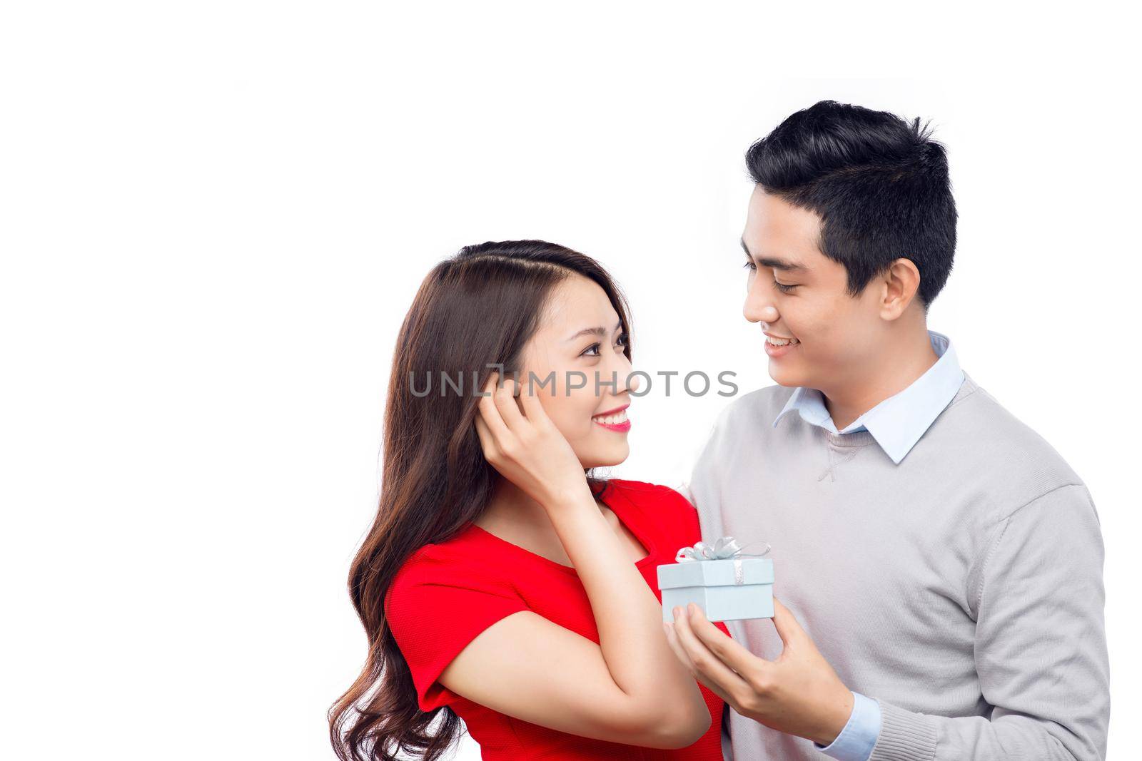 Asian man makes present to his lovely sweetheart. Young man giving a gift. Cheerful young couple man and woman at home offering to each other gifts for lover's valentine day by makidotvn