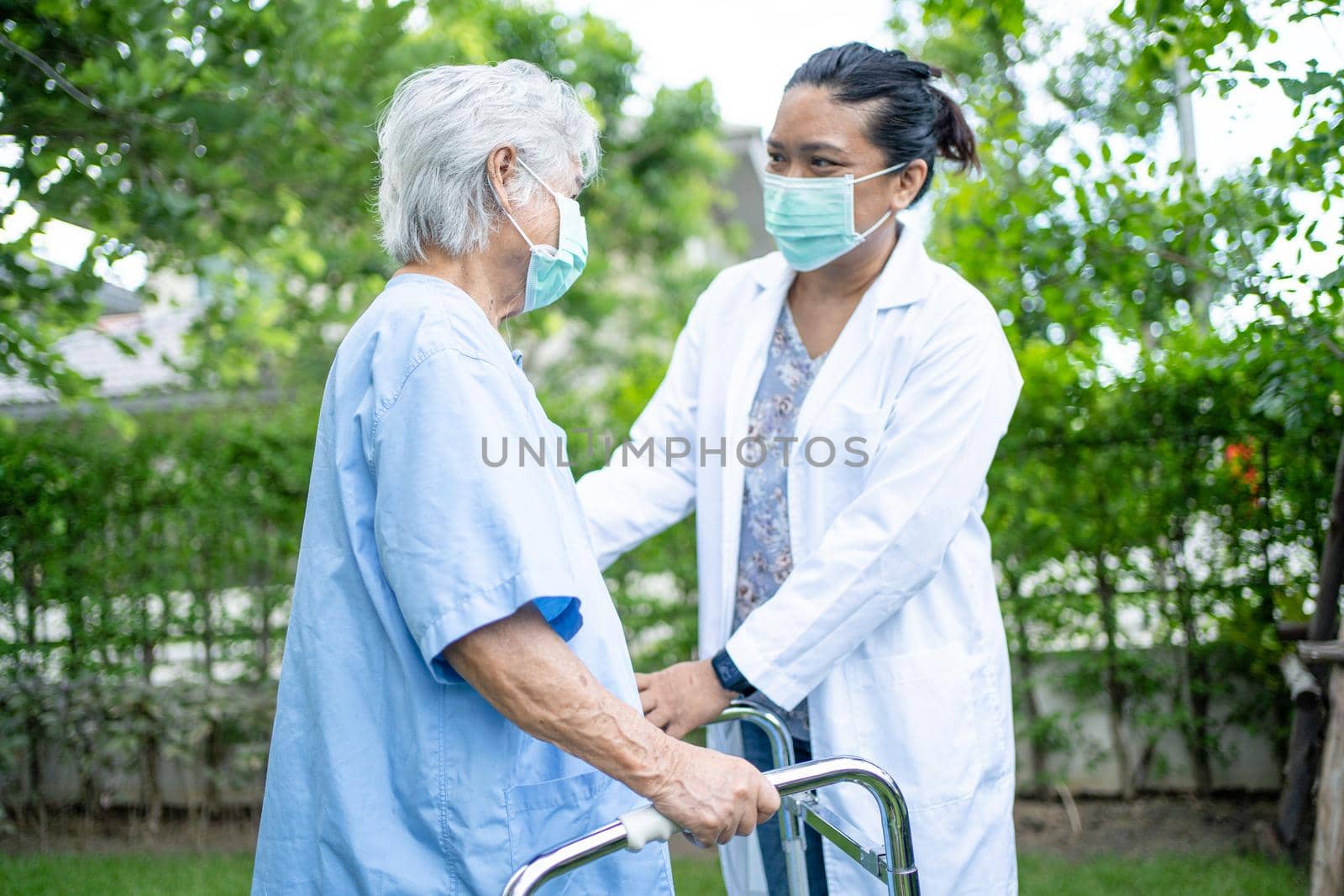 Help and care Asian senior or elderly old lady woman use walker with strong health while walking at park in happy fresh holiday. by pamai