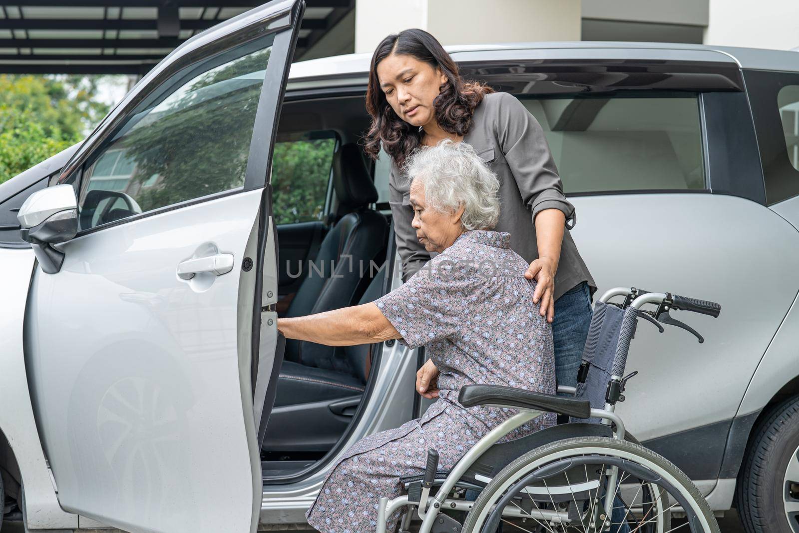 Help and support asian senior or elderly old lady woman patient prepare get to her car. by pamai