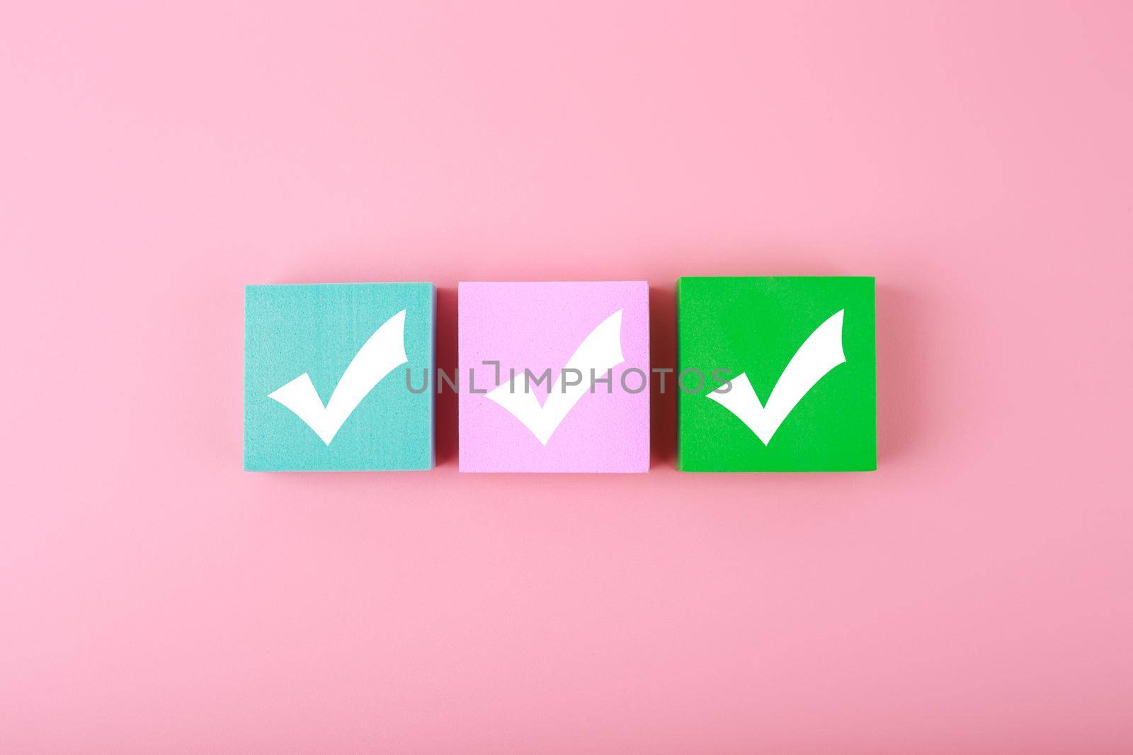 Three checkmarks on colorful blocks against pastel pink background  by Senorina_Irina