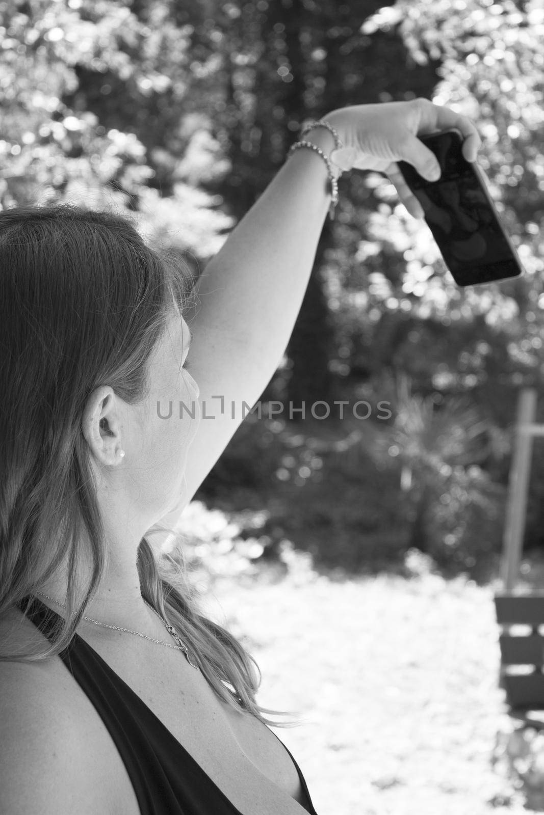 Seven month pregnant woman taking a selfie in a park