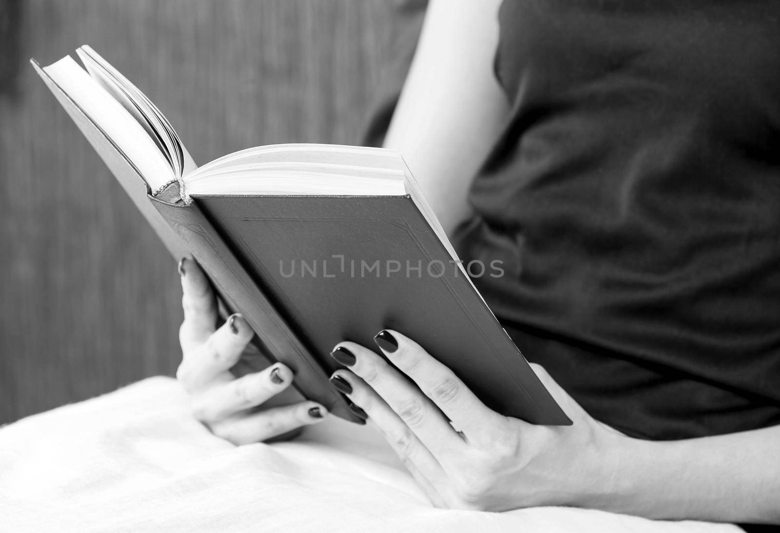 close up of young woman reading book in bed by Nobilior