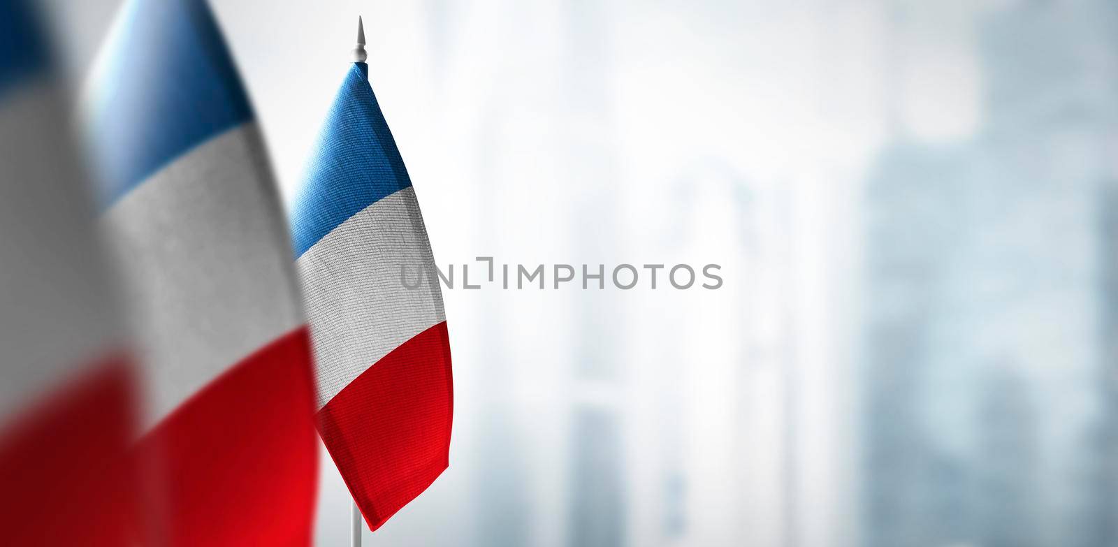 Small flags of France on a blurry background of the city.