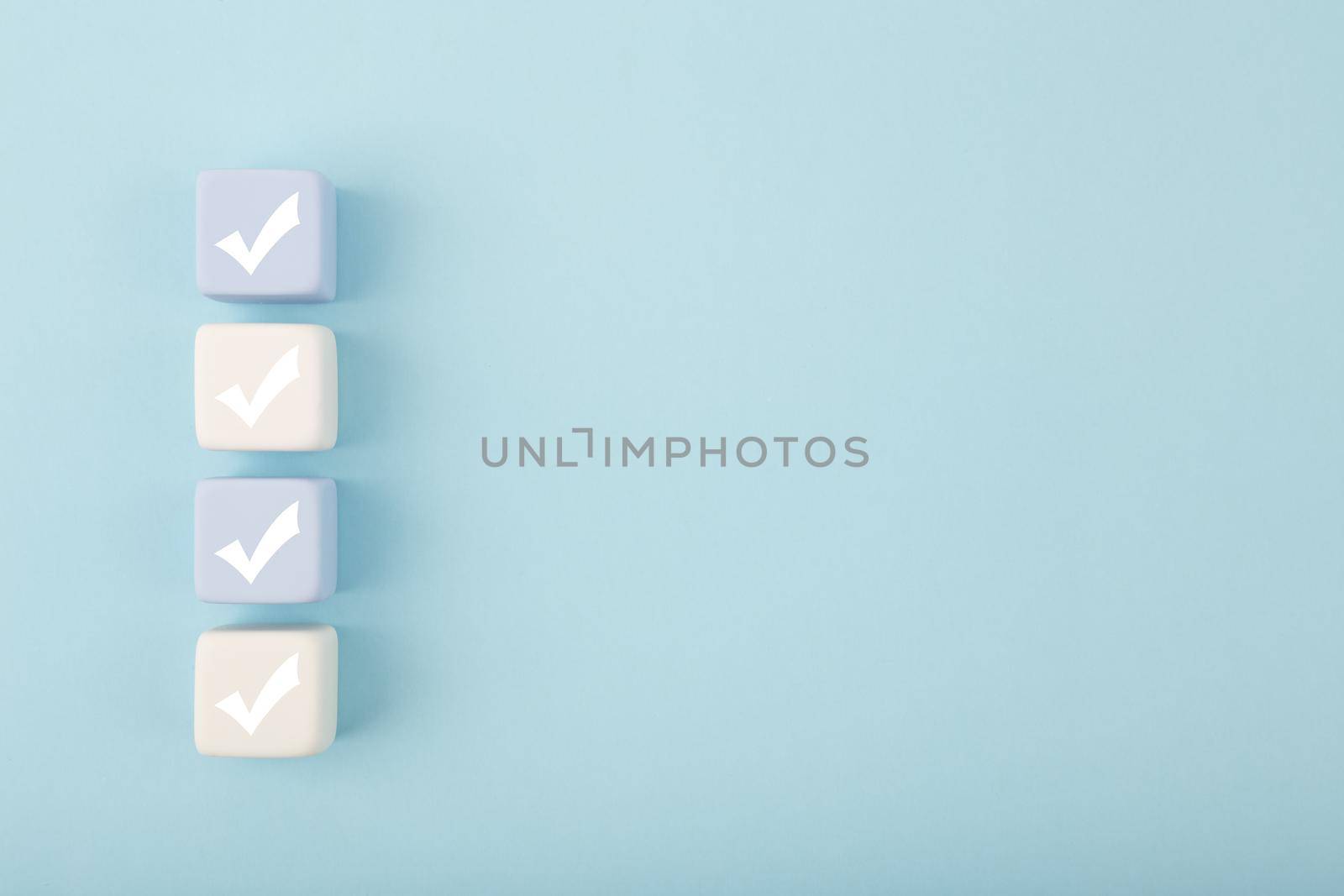 Four checkmarks on light toy blocks against pastel blue background with copy space by Senorina_Irina