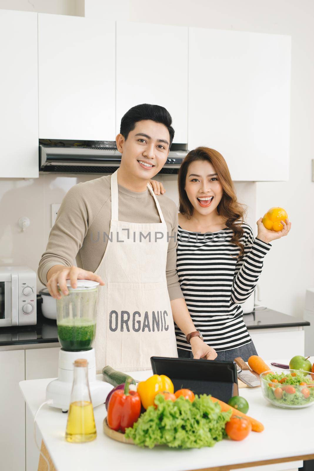 Happy asian couple in love in kitchen making healthy juice  by makidotvn