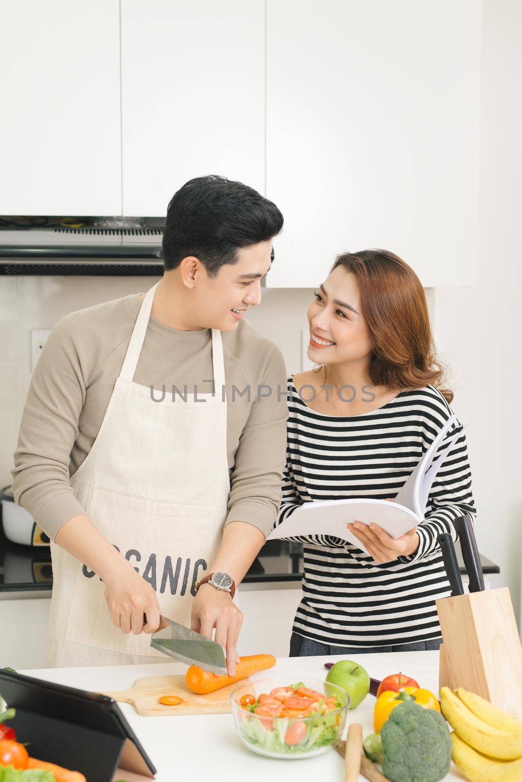 Loving happy couple preparing a healthy salad of fresh vegetables in the kitchen