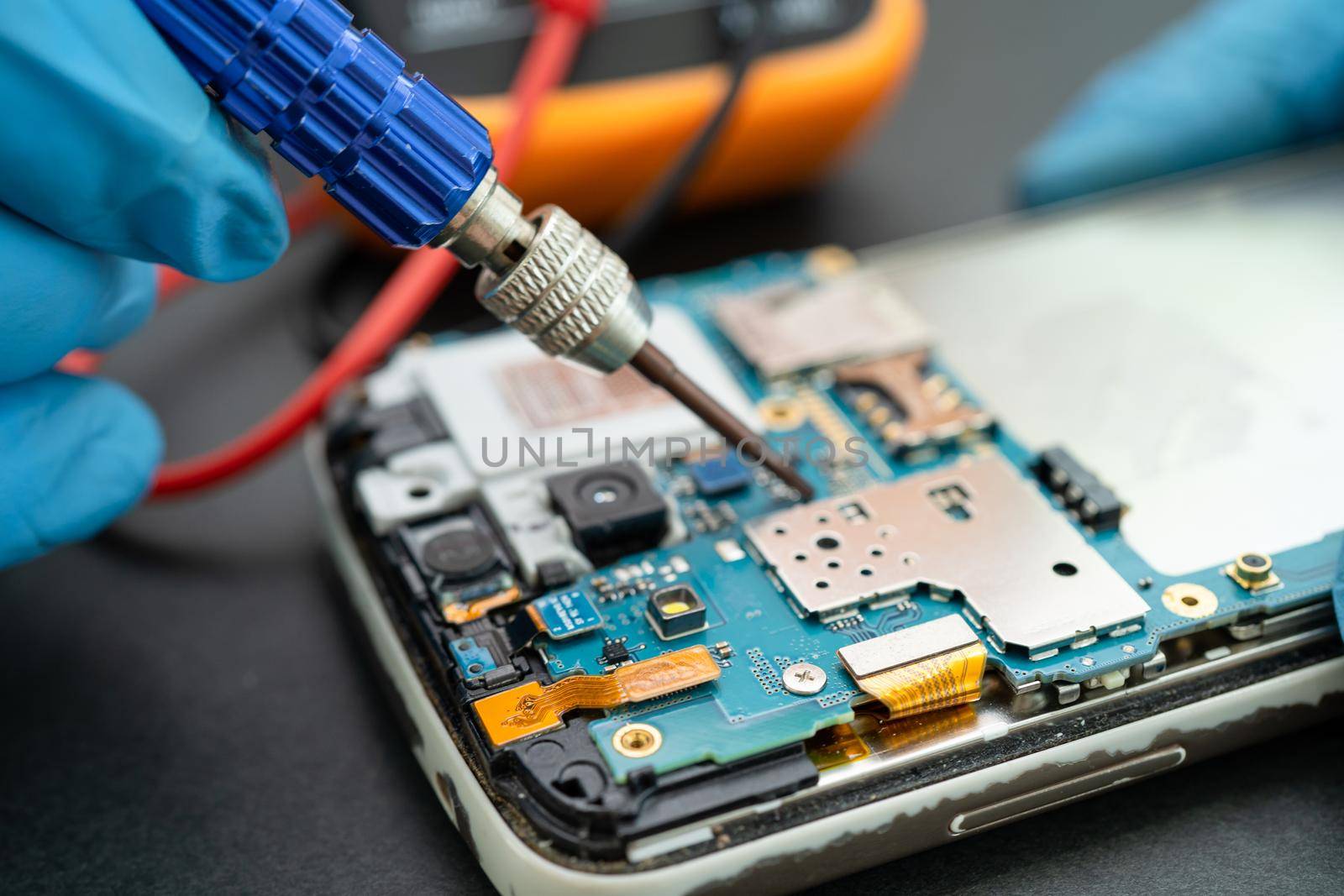 Technician repairing inside of mobile phone by soldering iron. Integrated Circuit. the concept of data, hardware, technology.