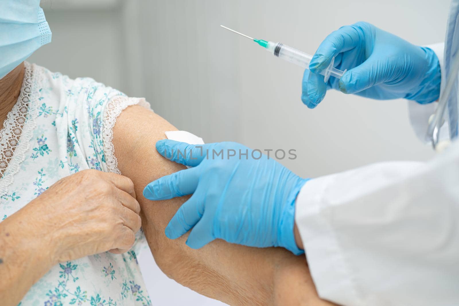 Elderly Asian senior woman wearing face mask getting covid-19 or coronavirus vaccine by doctor make injection.