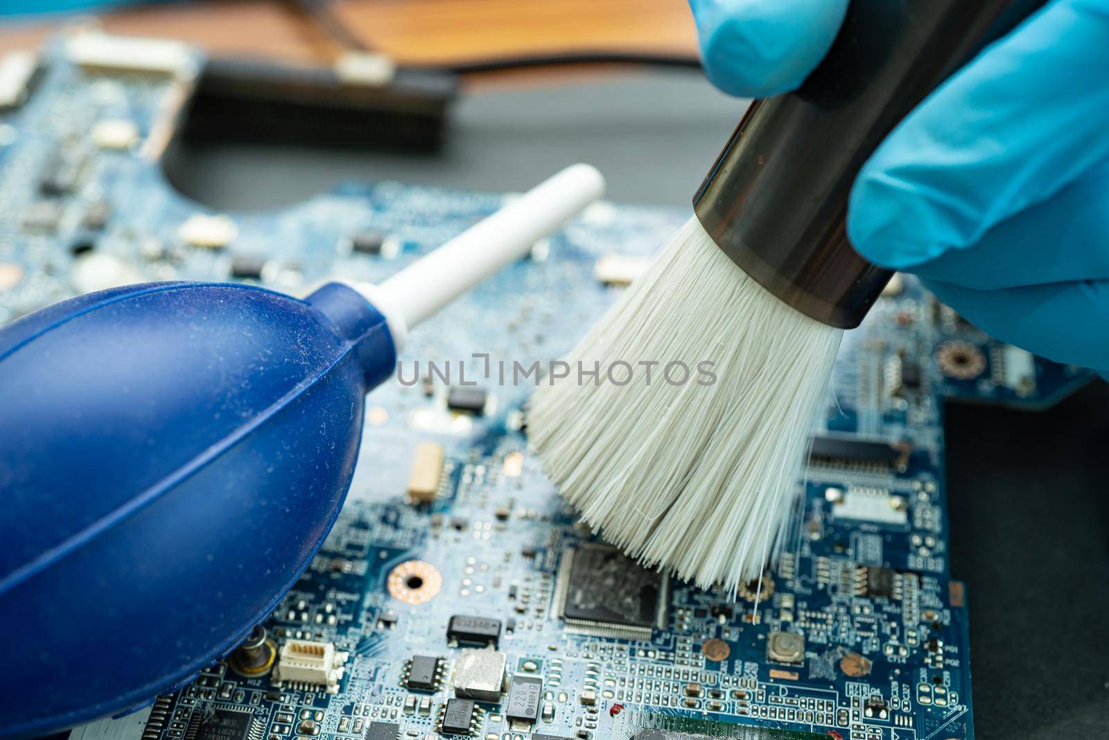 Technician use brush and air blower ball to clean dust in circuit board computer. Repair upgrade and maintenance technology. by pamai