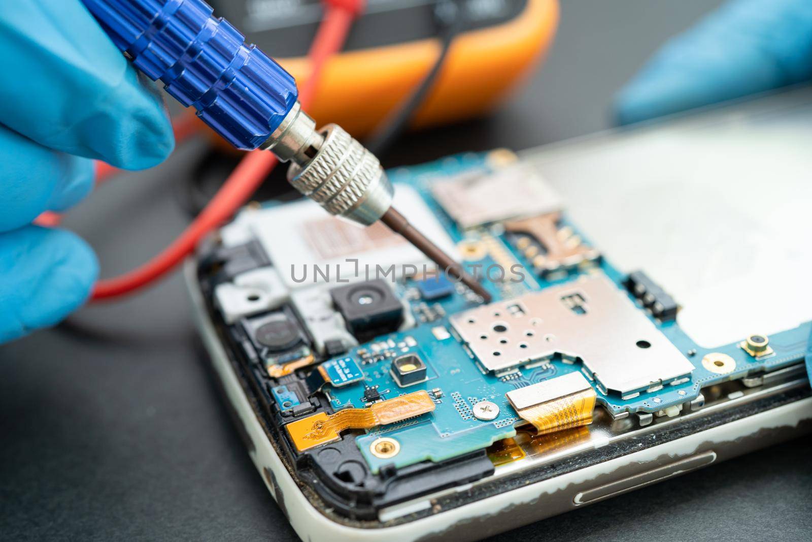 Technician repairing inside of mobile phone by soldering iron. Integrated Circuit. the concept of data, hardware, technology.