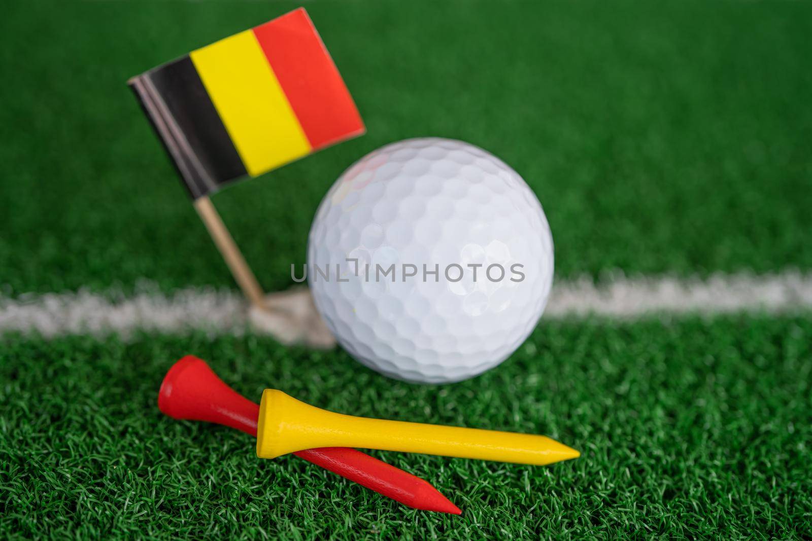 Golf ball with Germany flag and tee on green lawn or grass is most popular sport in the world.