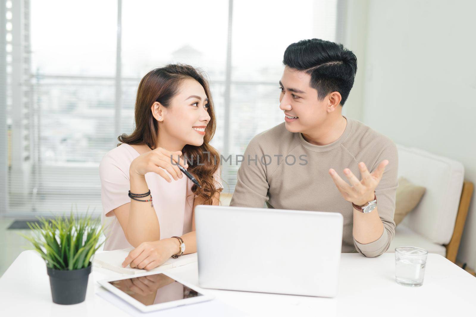 Happy businesswoman and businessman using laptop at workplace in office