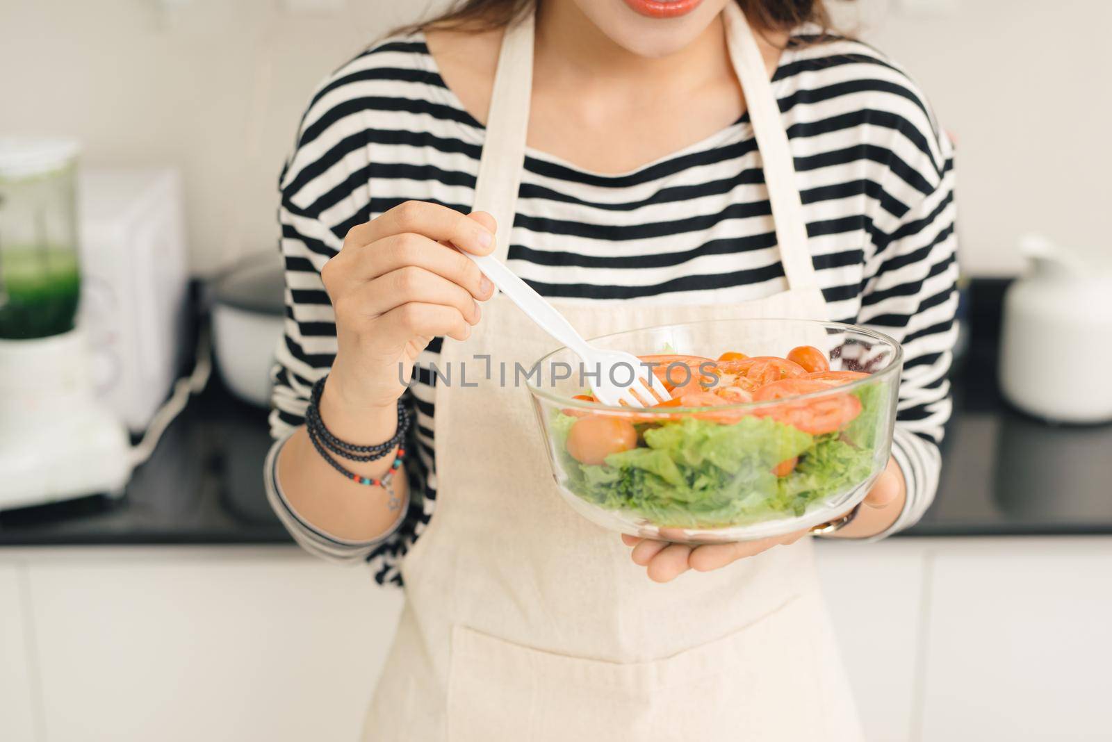 Young happy woman eating salad. Healthy lifestyle with green food. by makidotvn