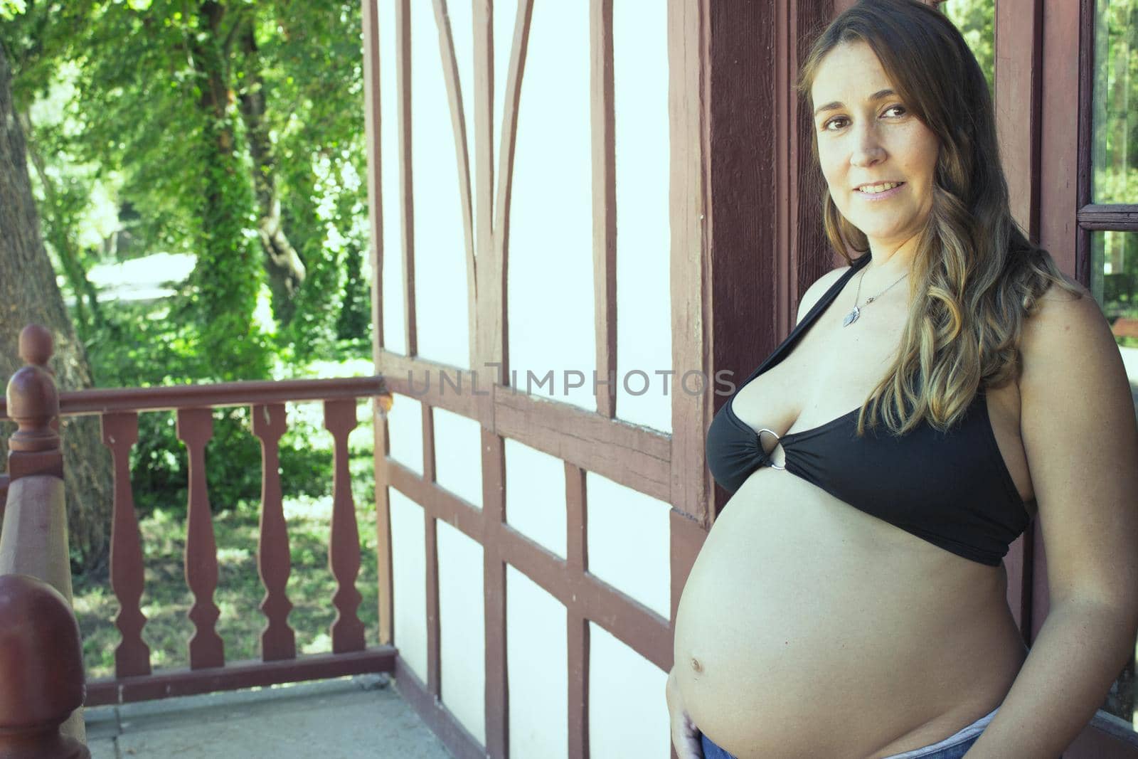 Seven months pregnant young woman dressed in black bikini and jeans