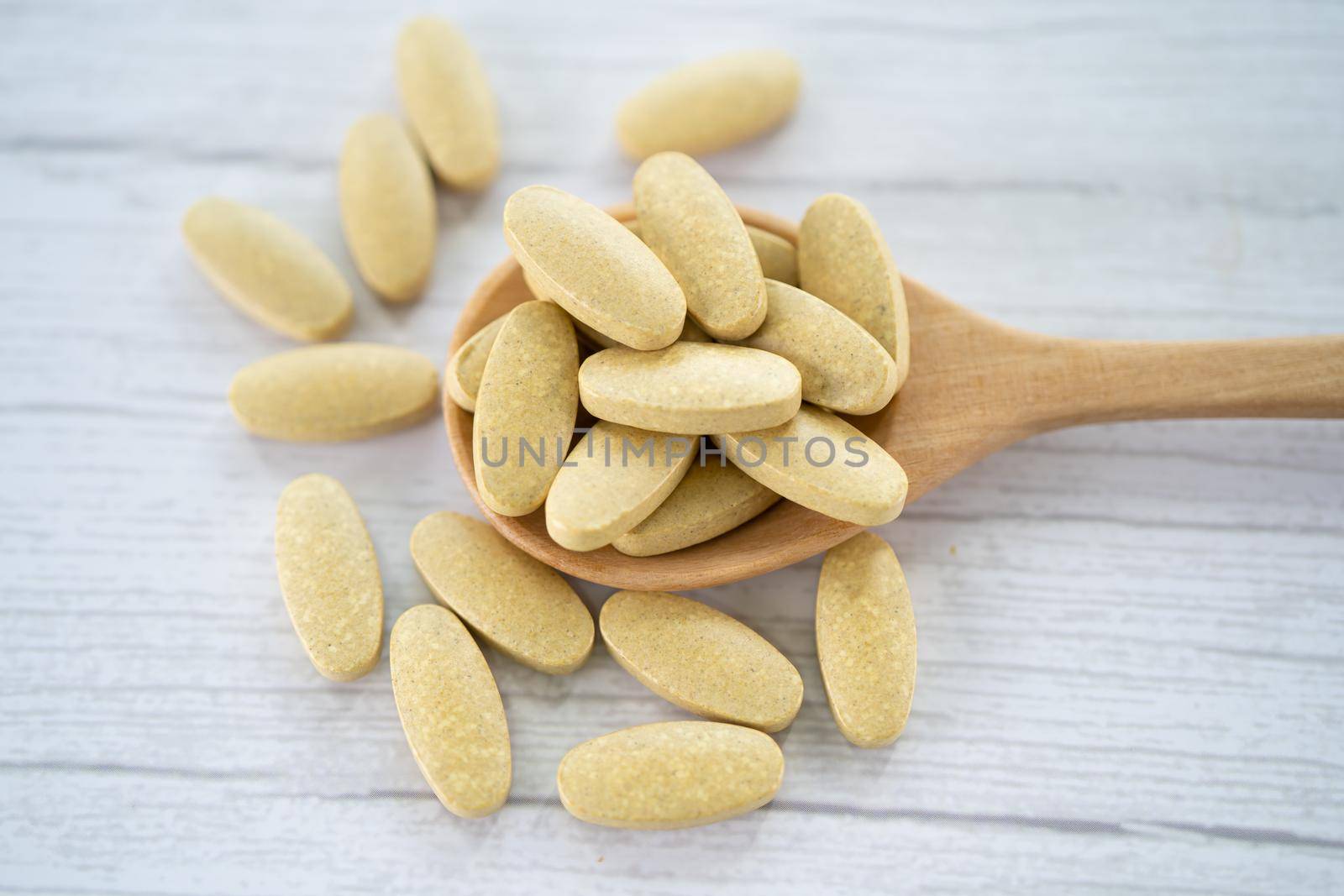 Vitamin C pills on wooden spoon for good health. by pamai