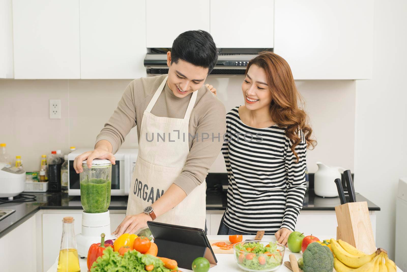 Portrait of happy asian young couple cooking together in the kitchen at home.