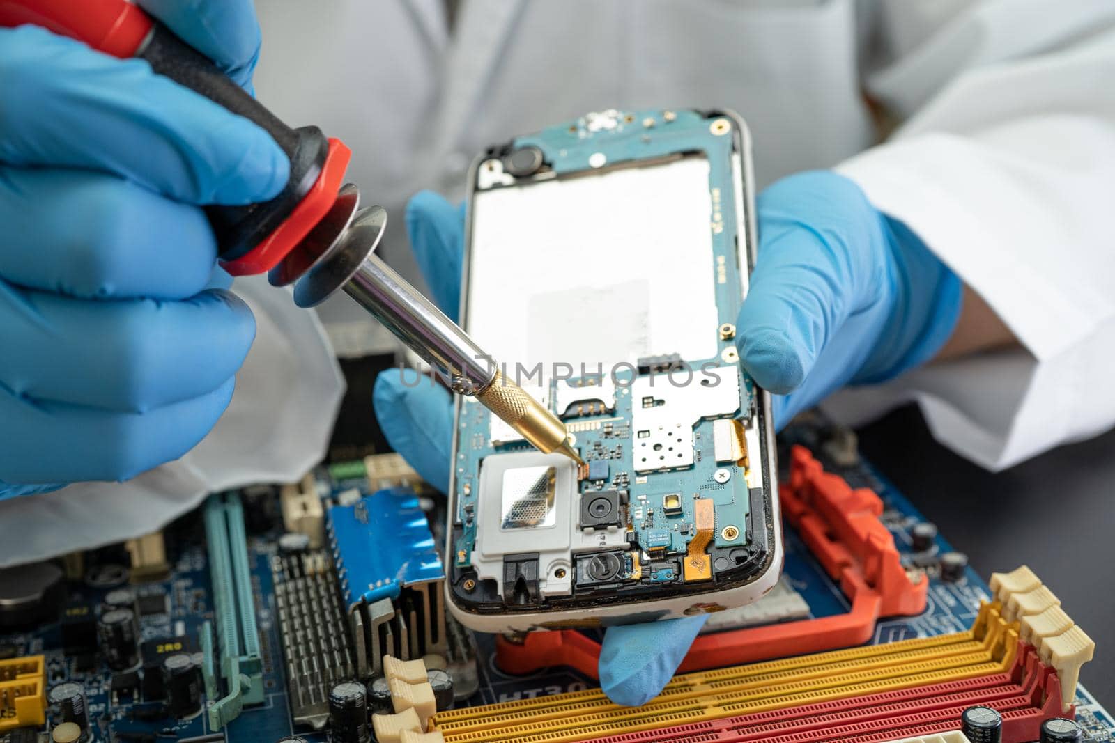 Technician repairing inside of mobile phone by soldering iron. Integrated Circuit. the concept of data, hardware, technology.