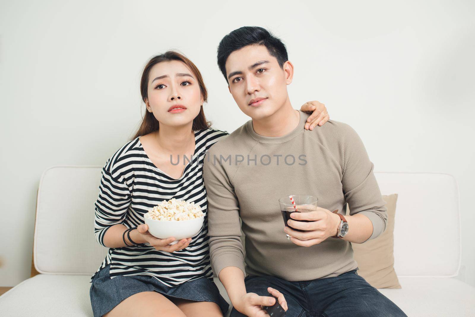 Bored young couple watching television at home