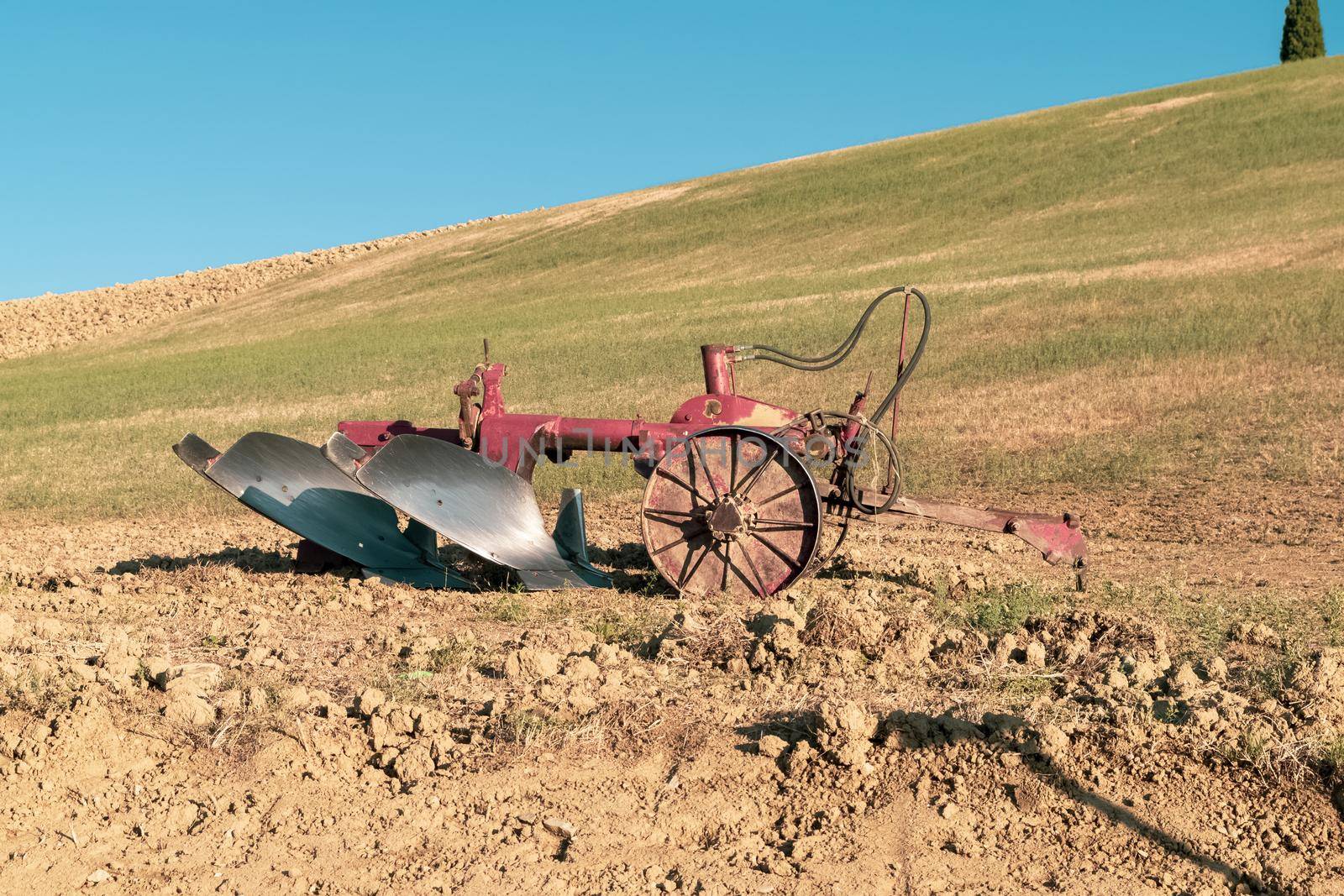 Closeup of a plow standing on a hill in the idyllic Tuscan countryside, Tuscany, Italy.