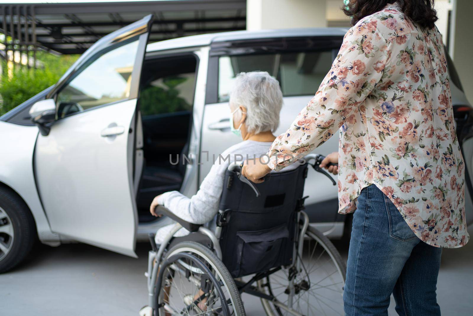 Help and support asian senior or elderly old lady woman patient sitting on wheelchair prepare get to her car, healthy strong medical concept. by pamai