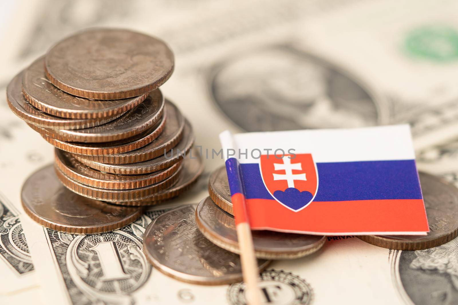 Stack of coins with Slovakia flag on US dollar banknotes background.