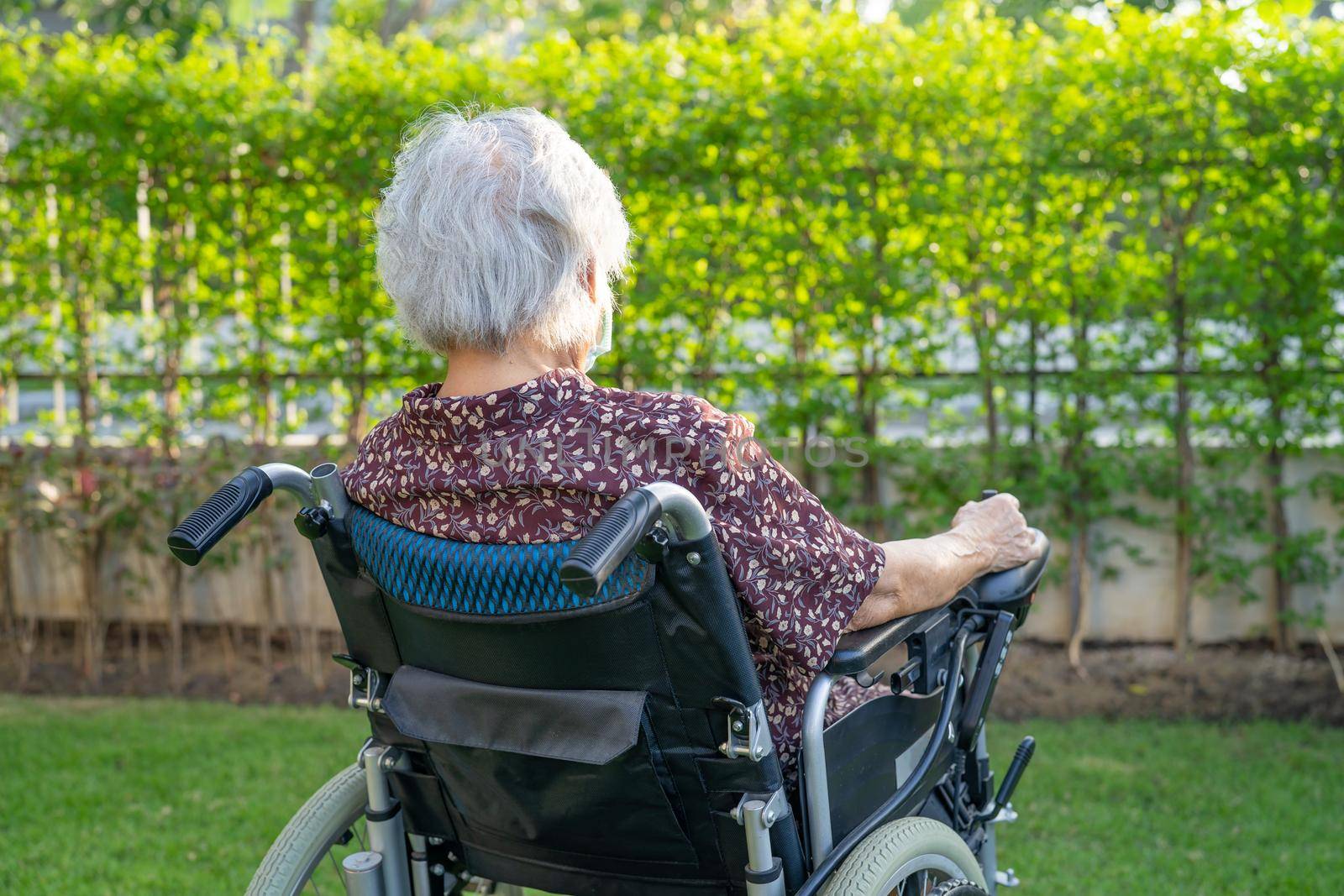 Asian senior woman patient on electronic wheelchair in park. by pamai