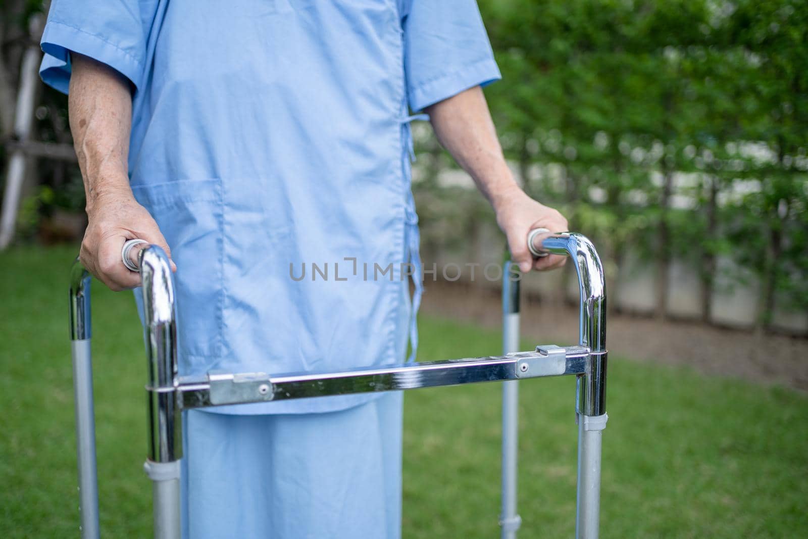 Asian senior or elderly old lady woman use walker with strong health while walking at park in happy fresh holiday. by pamai