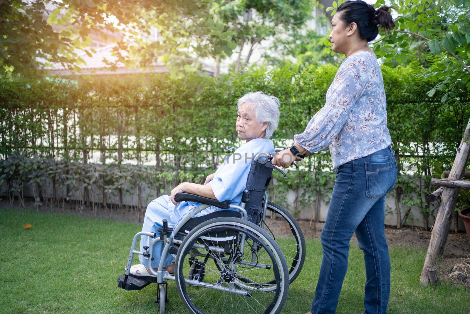 Doctor help and care Asian senior or elderly old lady woman patient sitting on wheelchair at park in nursing hospital ward, healthy strong medical concept. by pamai