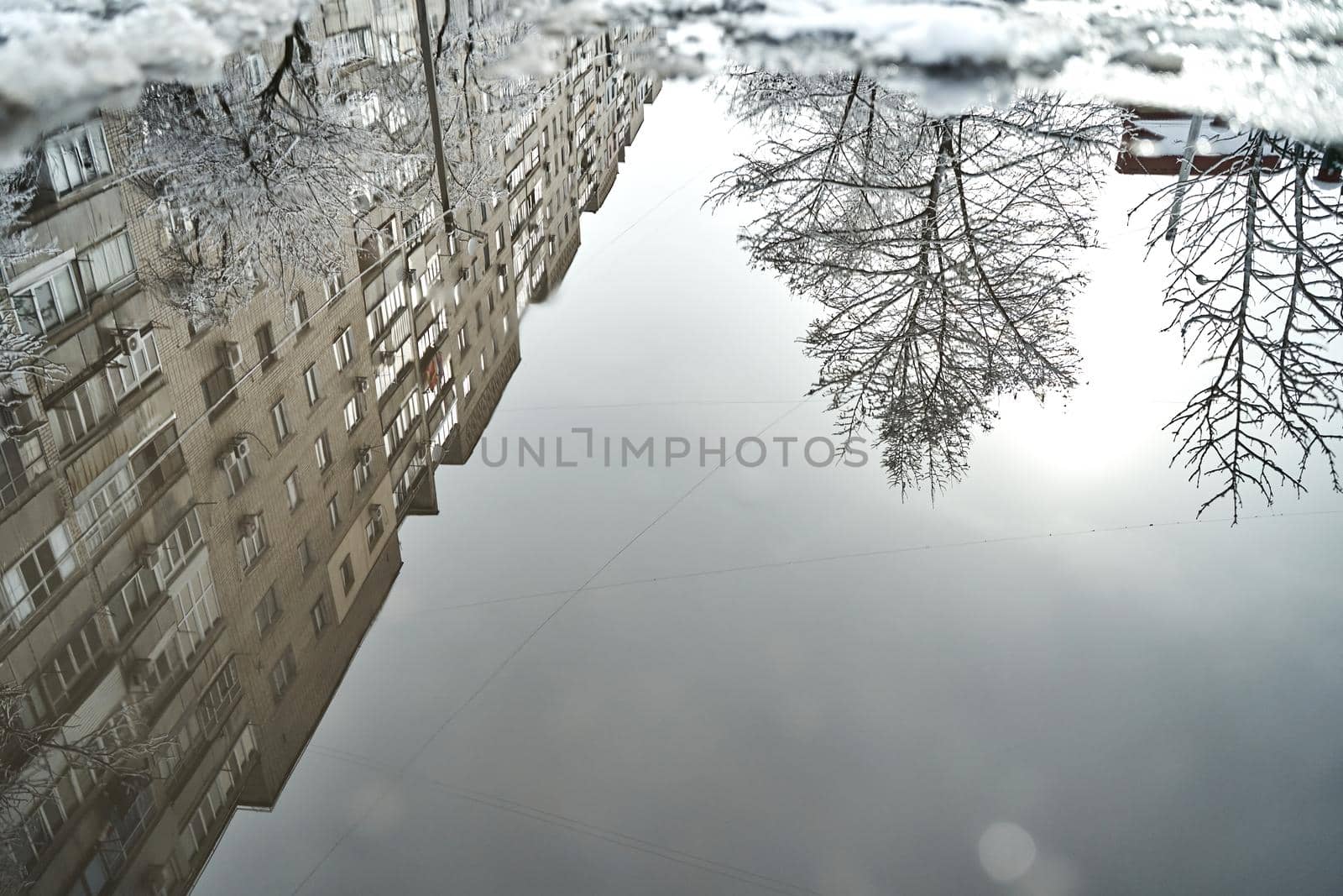 Reflection on the puddle of winter snow covered city scenery.